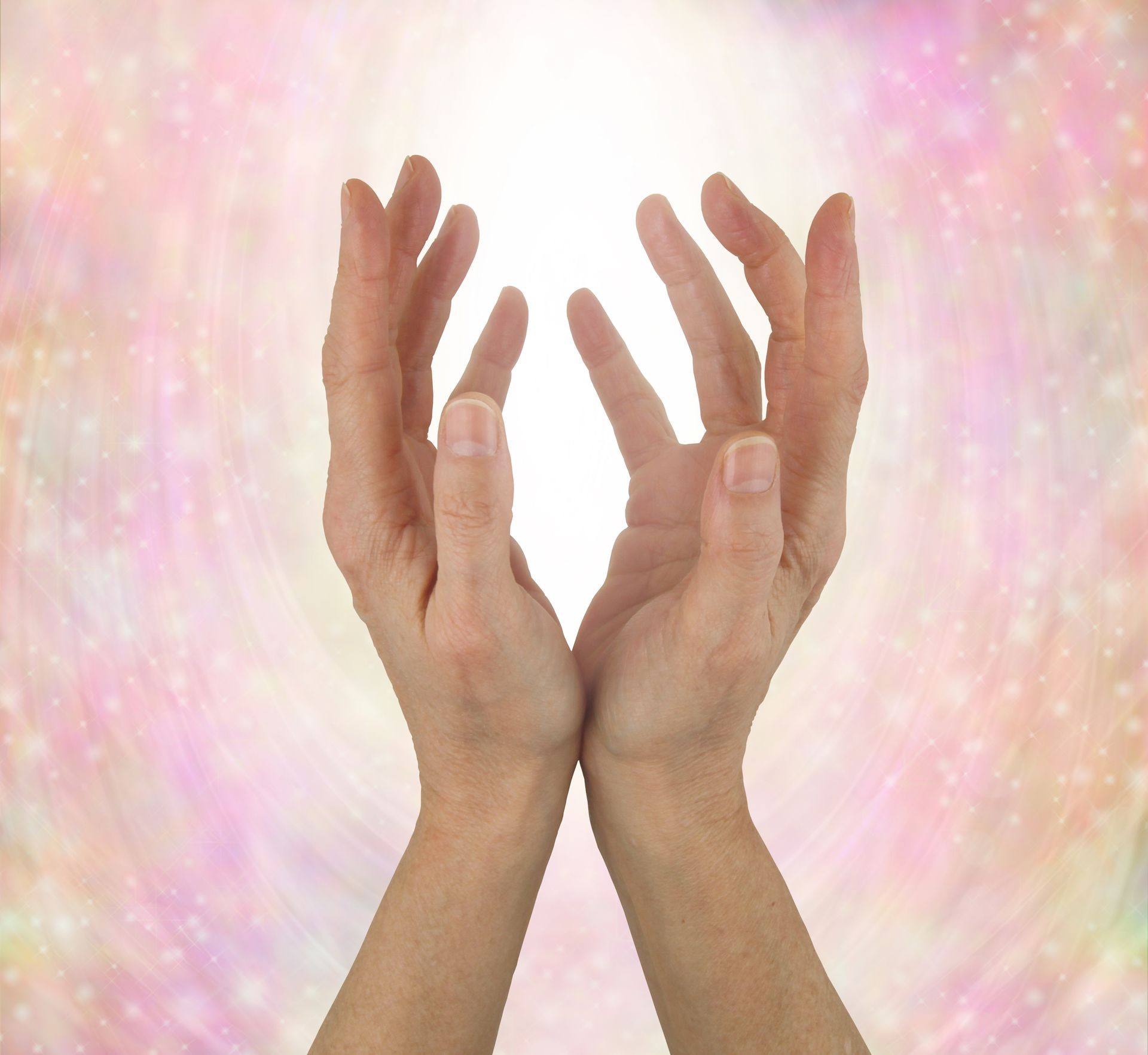 Quantum Healing Energy - female hands reaching upwards  sensing beautiful quantum healing in a soft pink resonating energy field                               
